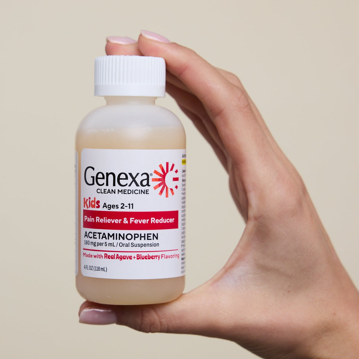 A hand holding a bottle of Genexa Kids Acetaminophen liquid medicine against a solid beige background.