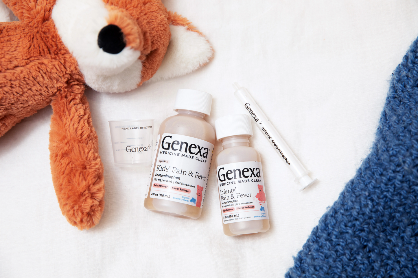 Genexa products including bottles and a syringe on a white surface with a plush toy fox and blue towel.